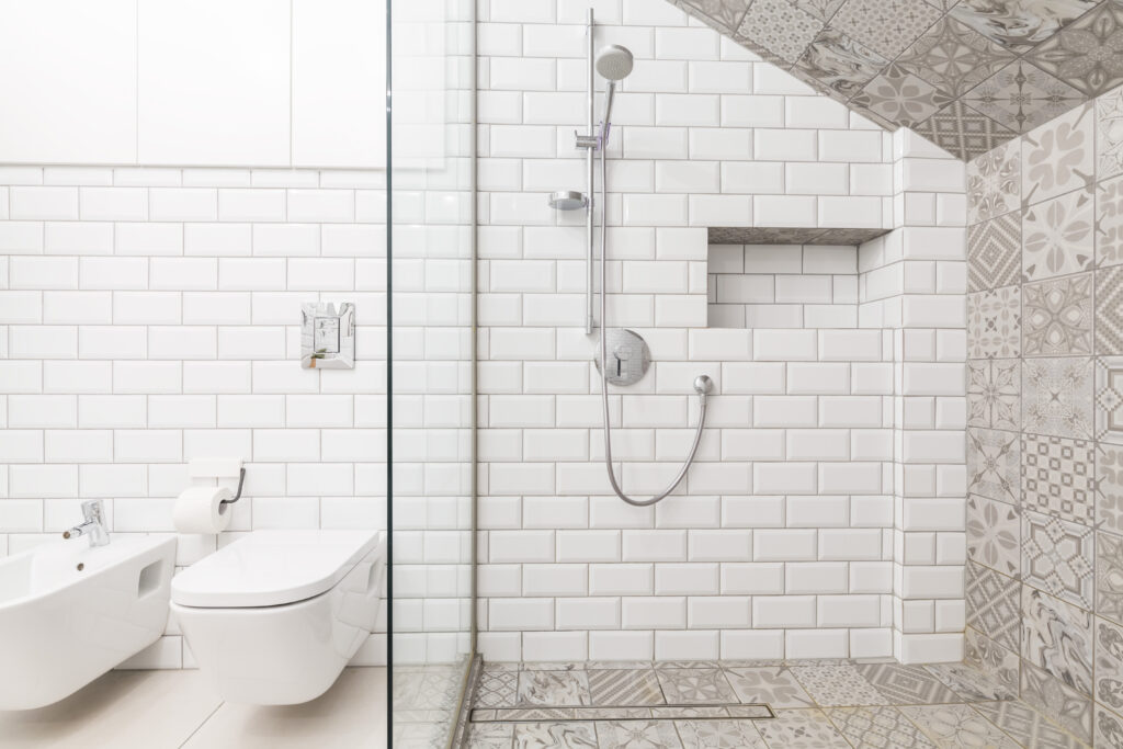 A spacious bathroom featuring a large walk-in shower with stylish tiles and a modern bathtub.